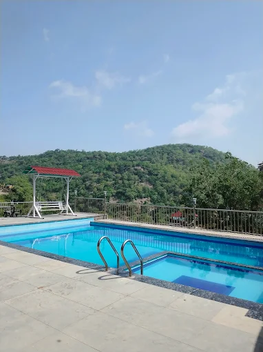 Outdoor swimming pool at Hotel Leopard Valley with views of the Aravalli hills